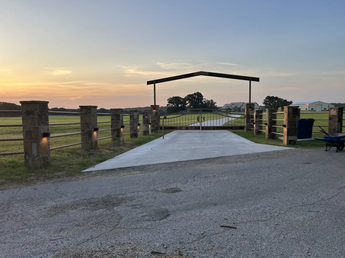 Enhanced driveway entry with stone gate at sunset in Weatherford TX